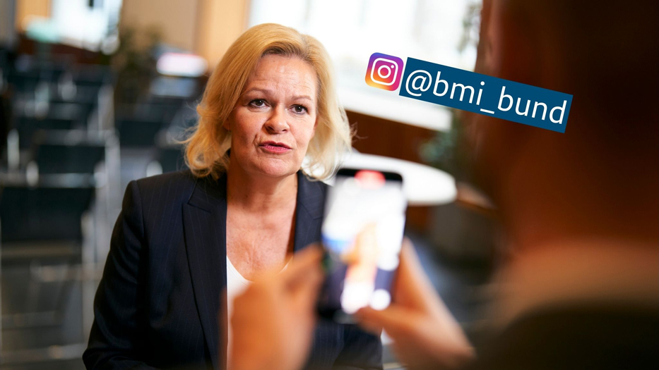 Bundesinnenministerin Faeser wird mit dem Handy gefilmt, neben ihr das Handle des BMI-Instagram-Kanals bmi_bund